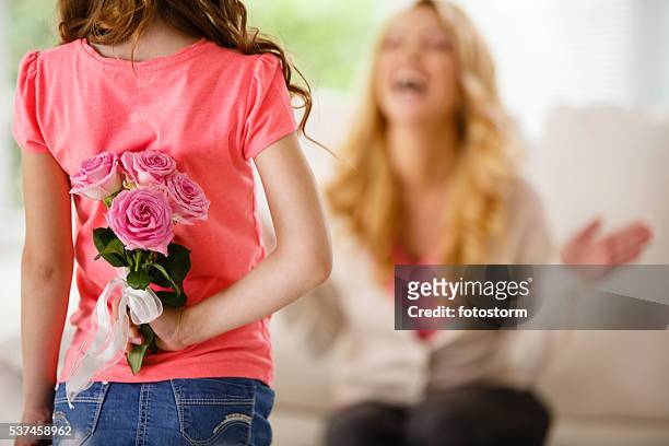 girl holding bouquet of roses behind back, surprising mother - mothers day flowers stock pictures, royalty-free photos & images