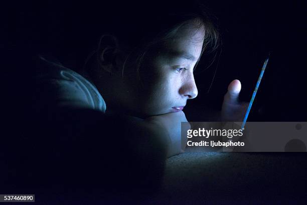 teenager sending email from smart phone in her bed - children stock pictures, royalty-free photos & images