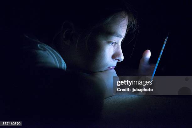 teenager sending email from smart phone in her bed - teenager stock pictures, royalty-free photos & images