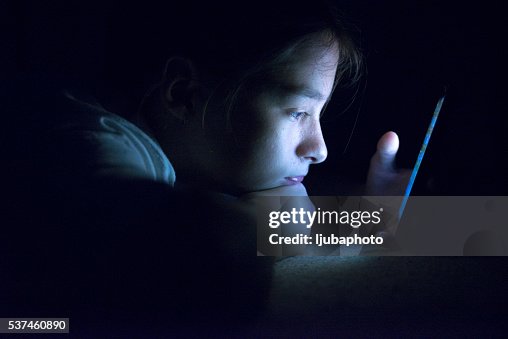 Teenager sending email from smart phone in her bed Teenager sending email from smart phone in her bed
