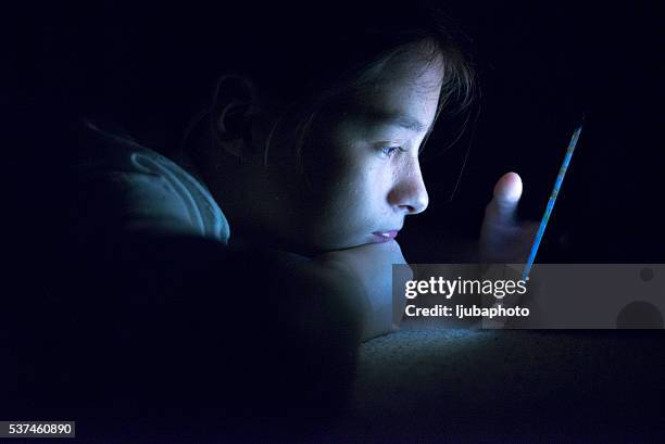 teenager sending email from smart phone in her bed - längtan bildbanksfoton och bilder