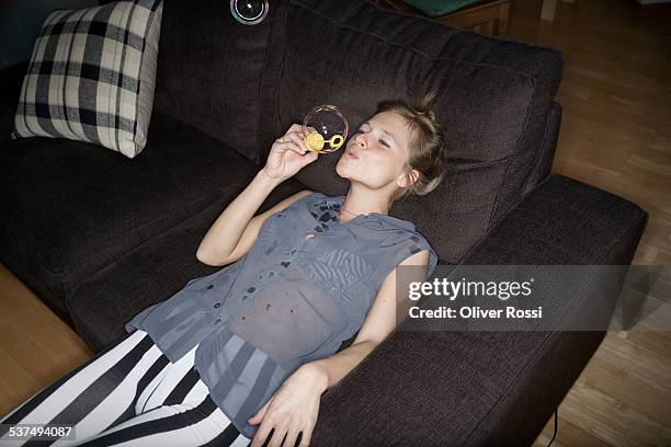 young woman at home blowing soap bubble - striped sofas stock pictures, royalty-free photos & images