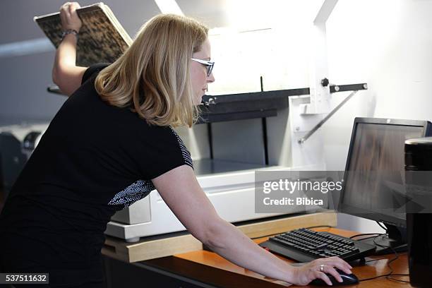 woman librarian scanning large sheets of newspaper - hand turning page stock pictures, royalty-free photos & images