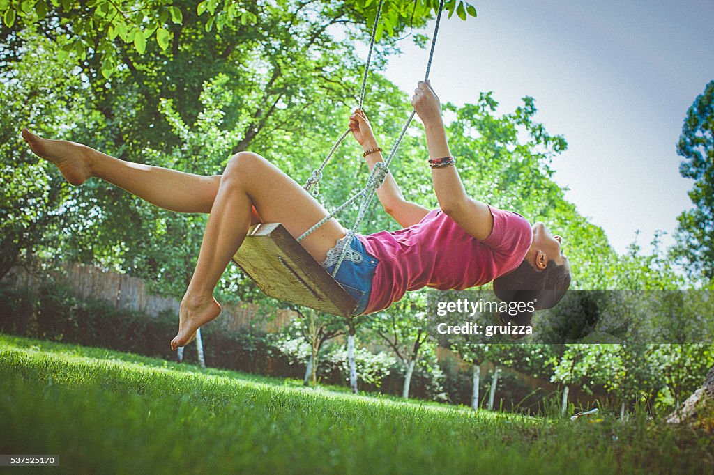 Glückliche junge Frau Spaß haben auf einer Schaukel im Park