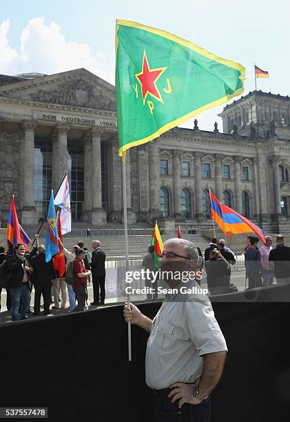 Man carrying a flag of the Kurdish YPG militias joins a gathering to demand the recognition of the Armenian genocide outside the Reichstag, where the...