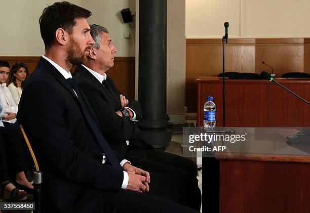 Barcelona's football star Lionel Messi and his father Jorge Horacio Messi listen as they face judges in a tax fraud case at the courthouse on June 2,...