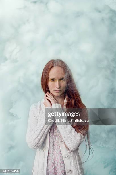 woman with long red hair, freckles and in white clothes standing in a blue smoke - thick white women ストックフォトと画像