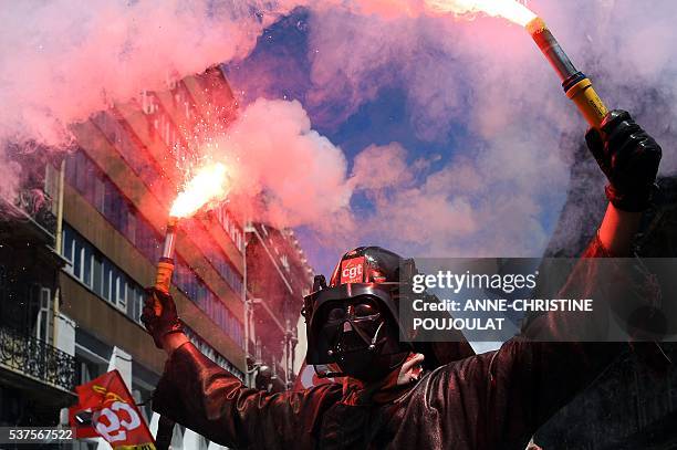 Man wearing a Dark Vador mask holds smoke flares during a demonstration against the French government's planned labour law reforms, on June 2, 2016...