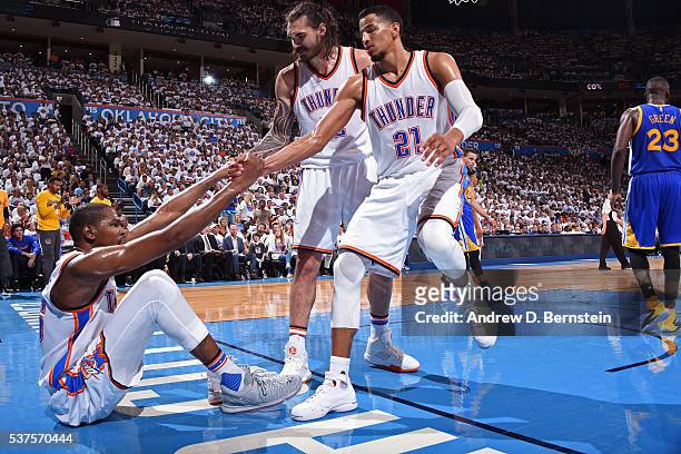 Steven Adams and Andre Roberson help up Kevin Durant of the Oklahoma City Thunder in Game Four of the Western Conference Finals against the Golden...