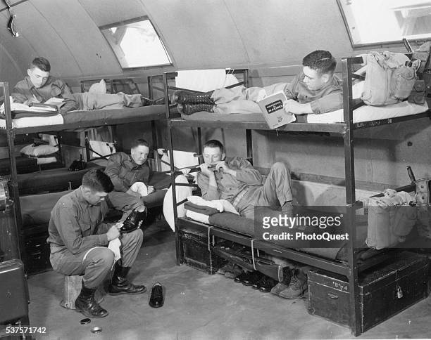 View of Marine recruits as they relax on bunks in a Quonset hut at boot camp, San Diego, California, June 6, 1955. One polishes his shoes, one...