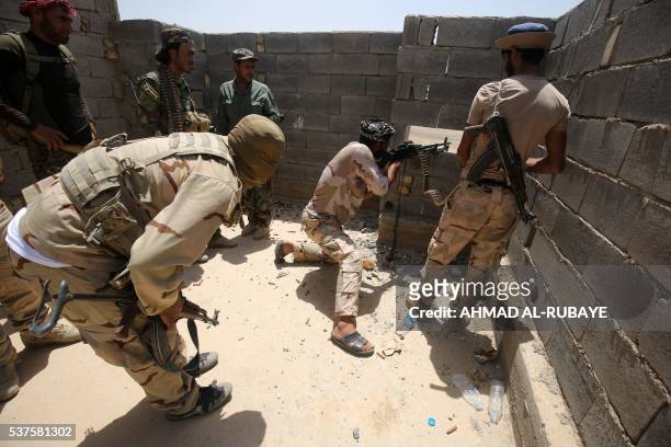 Iraqi government forces supported by the Popular Mobilisation units take cover behind a wall as they engage in combat in the Saqlawiyah area, north...