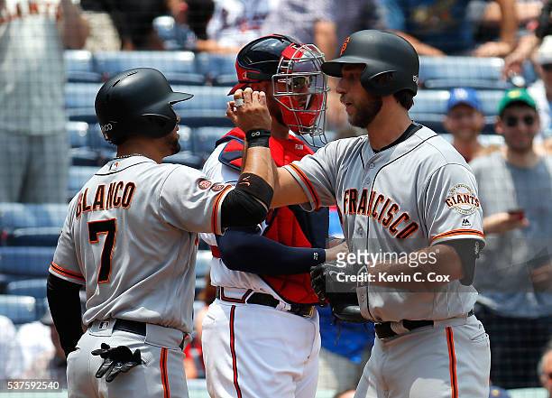 Madison Bumgarner of the San Francisco Giants reacts after hitting a two-run homer in the fifth inning against the Atlanta Braves that also scored...