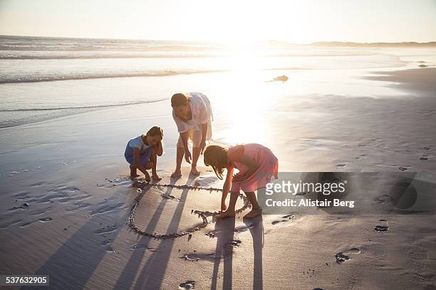 mother and daughter playing on beach - family drawing stock-fotos und bilder
