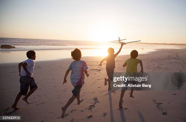 boys running along beach with a toy plane - bambini che corrono foto e immagini stock