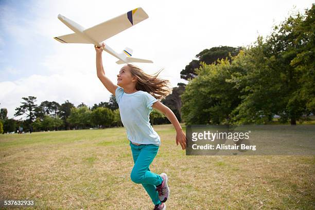 girl running in park with plane - toy airplane stock-fotos und bilder