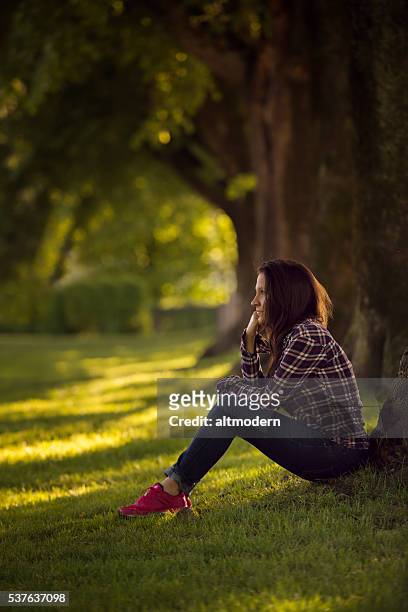 beautiful young women sitting in a park - attraktive frau stockfoto's en -beelden