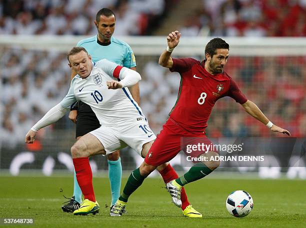 England's striker Wayne Rooney tackles Portugal's midfielder Joao Moutinho during the friendly football match between England and Portugal at Wembley...