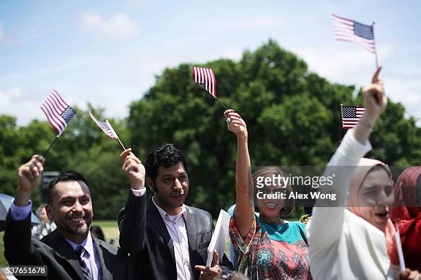 Newly naturalized citizens waves U.S. Flags as they participate in a naturalization ceremony June 2, 2016 at George Washington's Mount Vernon in...