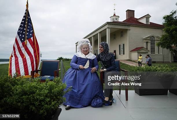 Mary Wiseman , a historical interpreter who portrays Martha Washington, greets a newly naturalized citizen as she is asked to to pose for a photos...