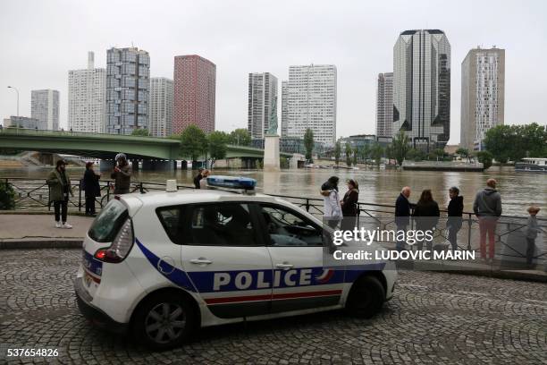 Picture taken on June 2, 2016 shows police patrolling along the river Seine bursting its banks in front of Beaugrenelle quarter, next to the statue...