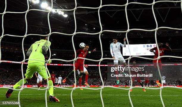 Chris Smalling of England beats Ricardo Carvalho and Danilo Pereira of Portugal as he scores their first goal past goalkeeper Rui Patricio of...