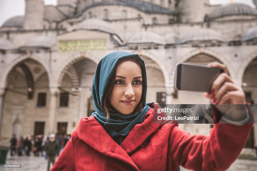 Woman taking a selfie in front of a mosque