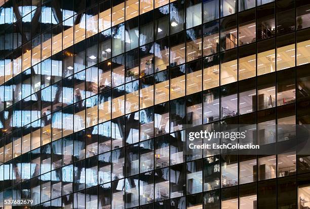 reflections in glass office facade at dusk - oficina fotografías e imágenes de stock