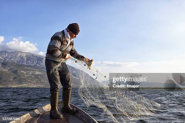 old fisherman on his boat - commercieel visnet stockfoto's en -beelden