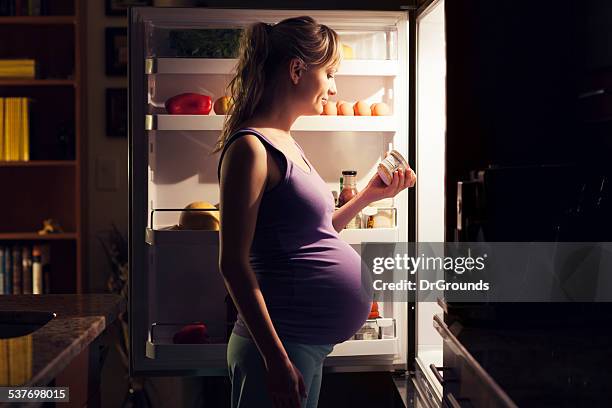 pregnant young woman at refrigerator choosing healthy food - bad habit stock pictures, royalty-free photos & images