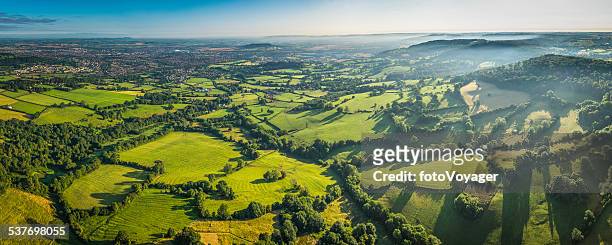 aerial panorama over green fields misty hills and country town - slyskog bildbanksfoton och bilder