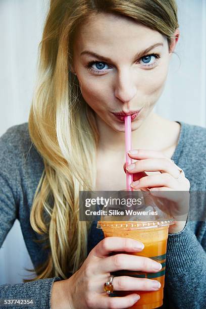 portrait of a handsome adult woman drinking a fruit smoothie in a cafe - woman drinking smoothie stock pictures, royalty-free photos & images