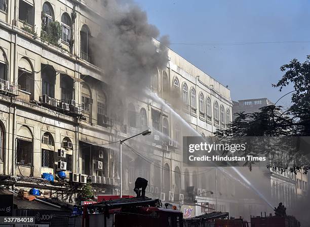 Firemen douse the fire which broke out inside the four-storey Metro House located at Colaba Causeway, near Regal Cinema, on June 2, 2016 in Mumbai,...