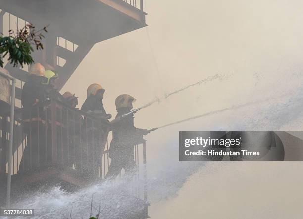 Firemen douse the fire which broke out inside the four-storey Metro House located at Colaba Causeway, near Regal Cinema, on June 2, 2016 in Mumbai,...
