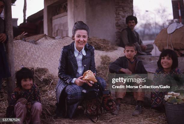 Western woman poses with Afghani children at the melon market in Kabul, Afghanistan. November, 1973. .