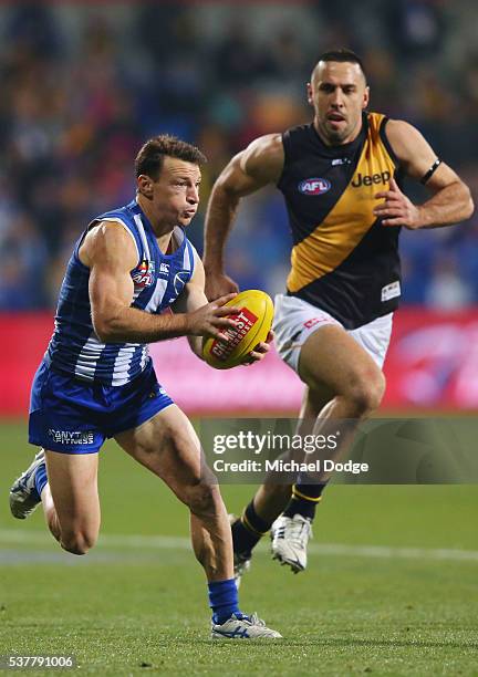 Brent Harvey of the Kangaroos runs with the ball away from Troy Chaplin of the Tigers during the round 11 AFL match between the North Melbourne...