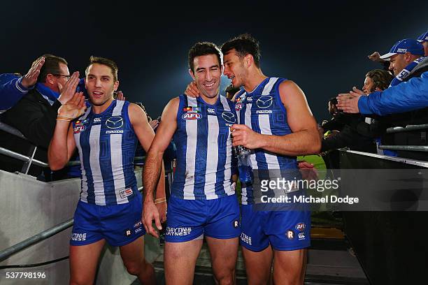 Jamie Macmillan of the Kangaroos Michael Firrito and Robbie Tarrant celebrate the win with fans during the round 11 AFL match between the North...