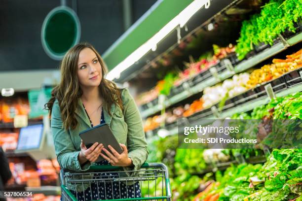 bella mujer con tableta de compra de comestibles - lista de la compra fotografías e imágenes de stock