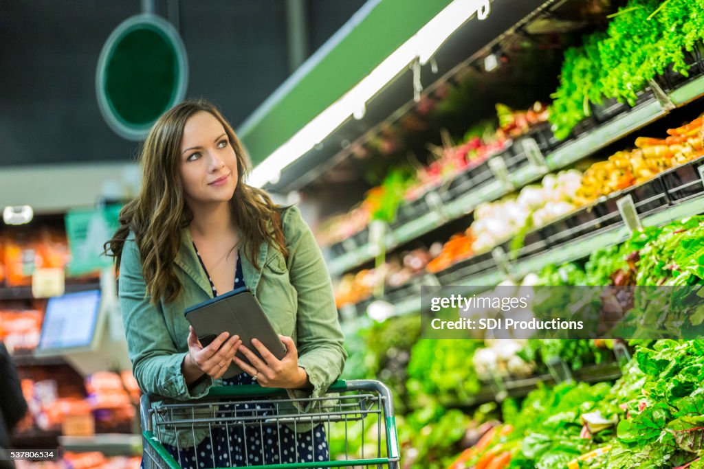Beautiful woman grocery shopping with tablet