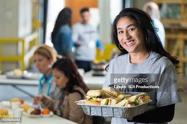 volunteer holding tablett mit sandwiches, serviert gerichte im food bank - soup kitchen stock-fotos und bilder