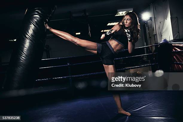female kickboxer fighter training with a punching bag - kicking bag stock pictures, royalty-free photos & images