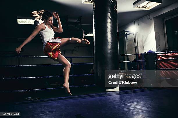 female muay thai fighter training with a punching bag - female boxer stock pictures, royalty-free photos & images