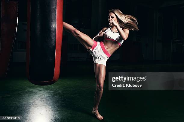 female kickboxer fighter training with a punching bag - kicking bag stock pictures, royalty-free photos & images