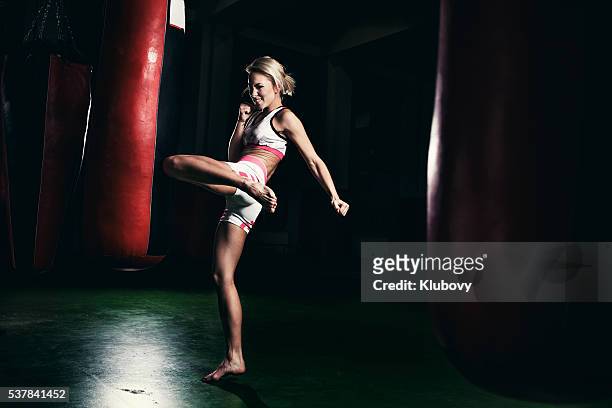 femme kick boxing formation de avec un sac de frappe - arts martiaux photos et images de collection