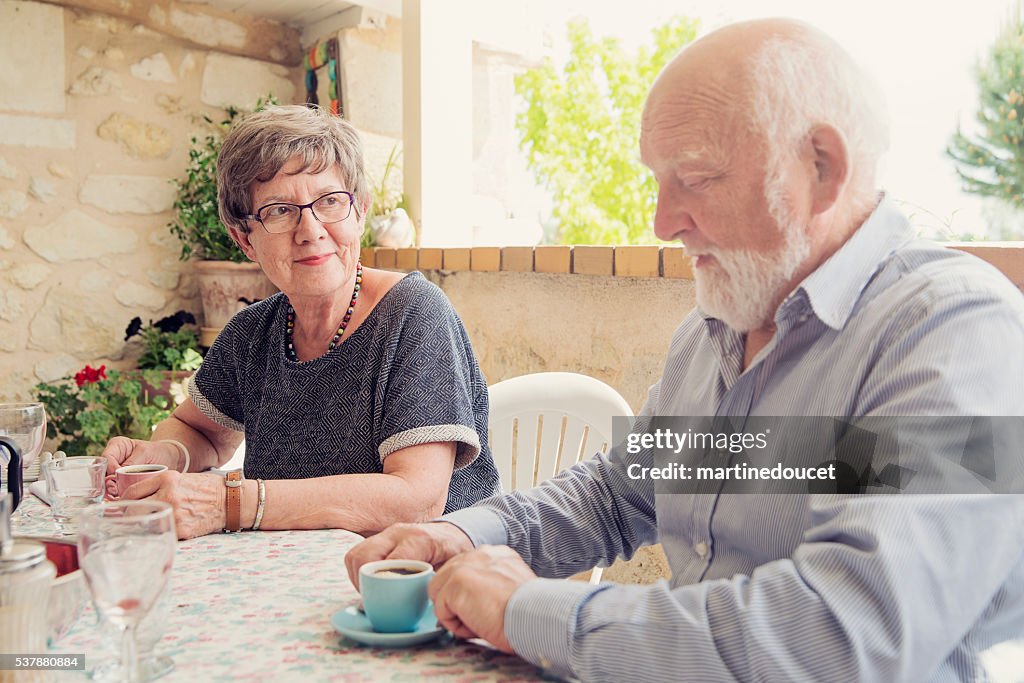 Coppia di persone anziane una certa età beve il caffè su una terrazza all'aperto in estate.