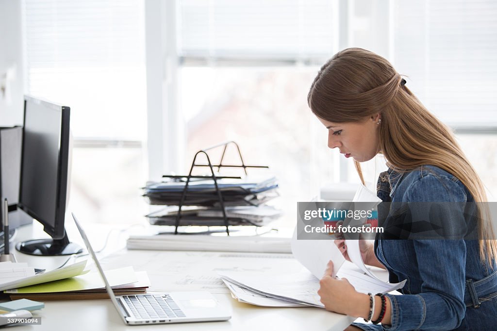 Businesswoman reading documents at desk in office