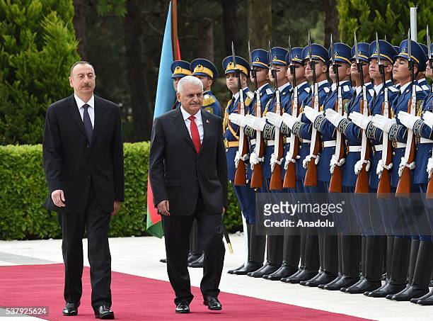 Azerbaijani President Ilham Aliyev and Turkish Prime Minister Binali Yildirim salute honor guards at the Zagulba Presidential Palace in Baku,...
