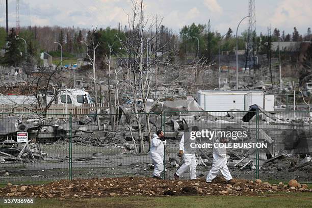 Workers walk past the wreckage of Beacon Hill neighbourhood of Fort McMurray, Alberta on June 3, 2016. The pace of Fort McMurray residents' return to...