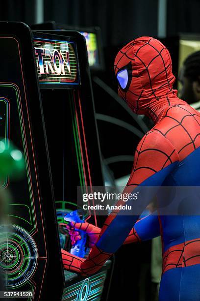 An attendee dressed as Spider-Man plays an original Tron arcade cabinet at Awesome Con, which is being held at the Washington Convention Center from...