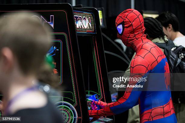 An attendee dressed as Spider-Man plays an original Tron arcade cabinet at Awesome Con, which is being held at the Washington Convention Center from...