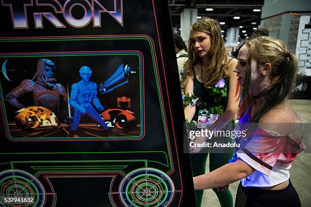 Two attendees dressed as Harley Quinn and Poison Ivy from the Batman series play an original Tron arcade cabinet at Awesome Con, which is being held...